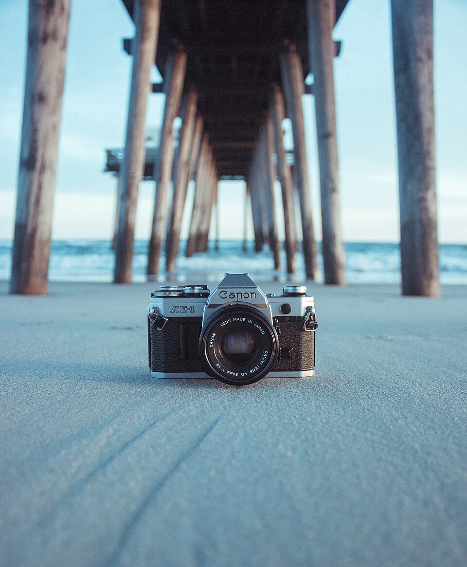 A film SLR on the sand under a pier
